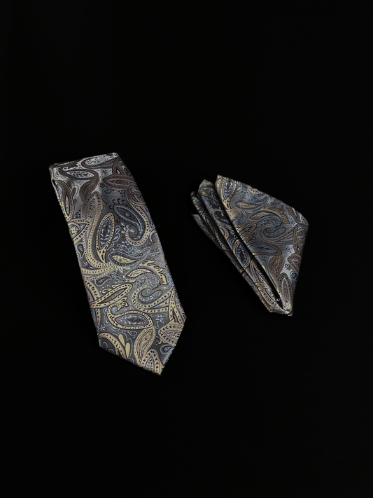A matching necktie and pocket square set with an intricate paisley pattern in gray, gold, and beige.