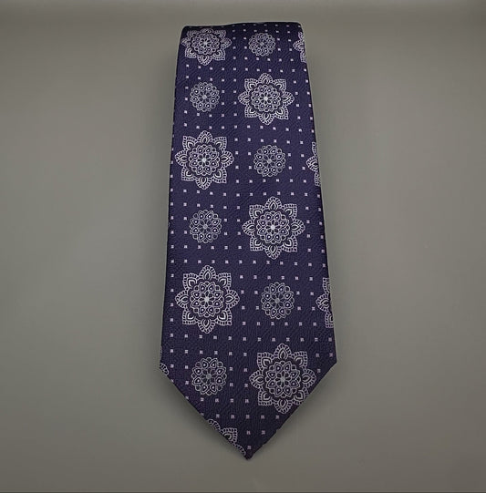 A classic necktie with a deep purple base and a detailed geometric medallion pattern in lavender, royal purple and silver.